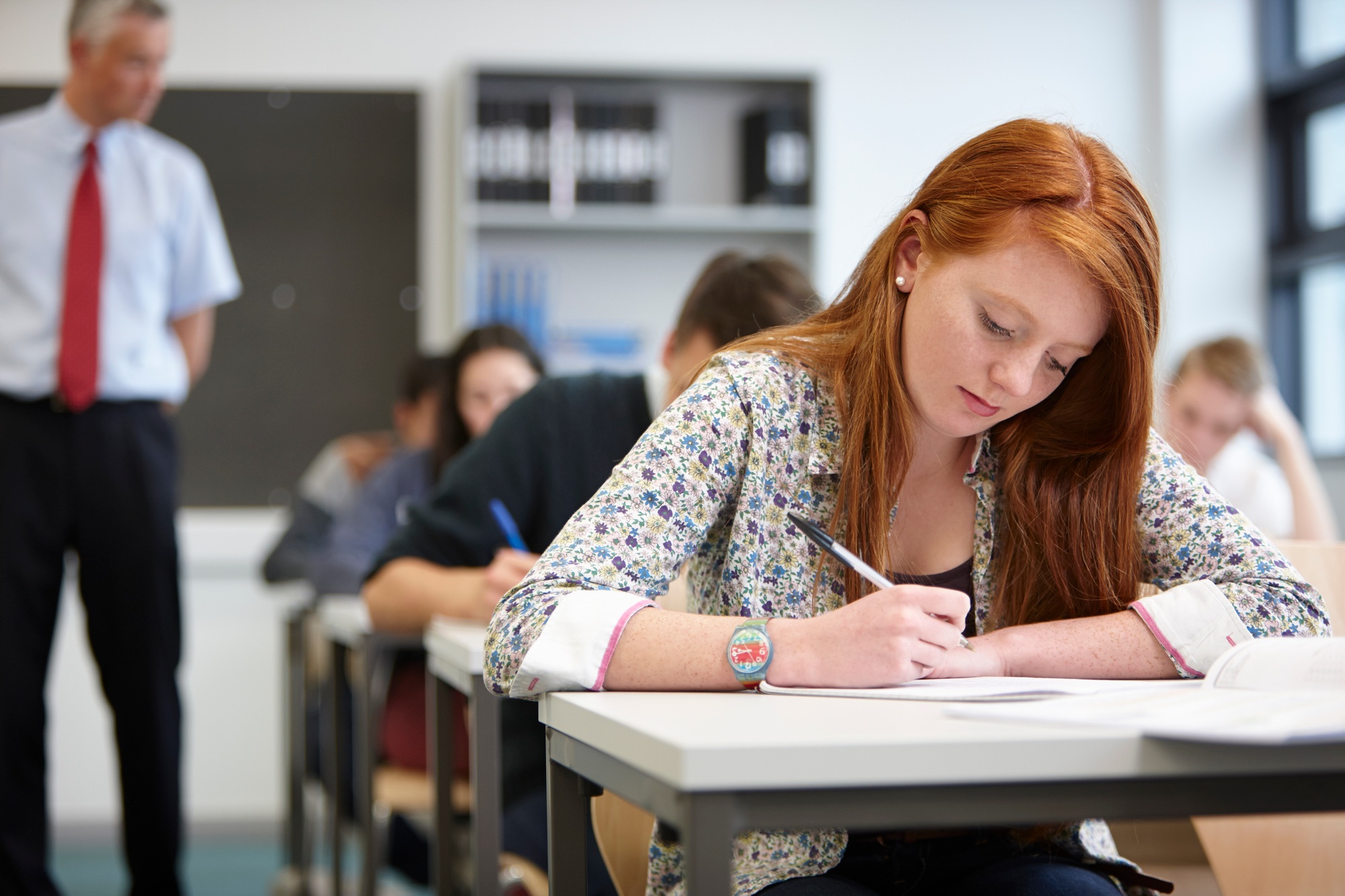 Teacher watching over teenagers in classroom