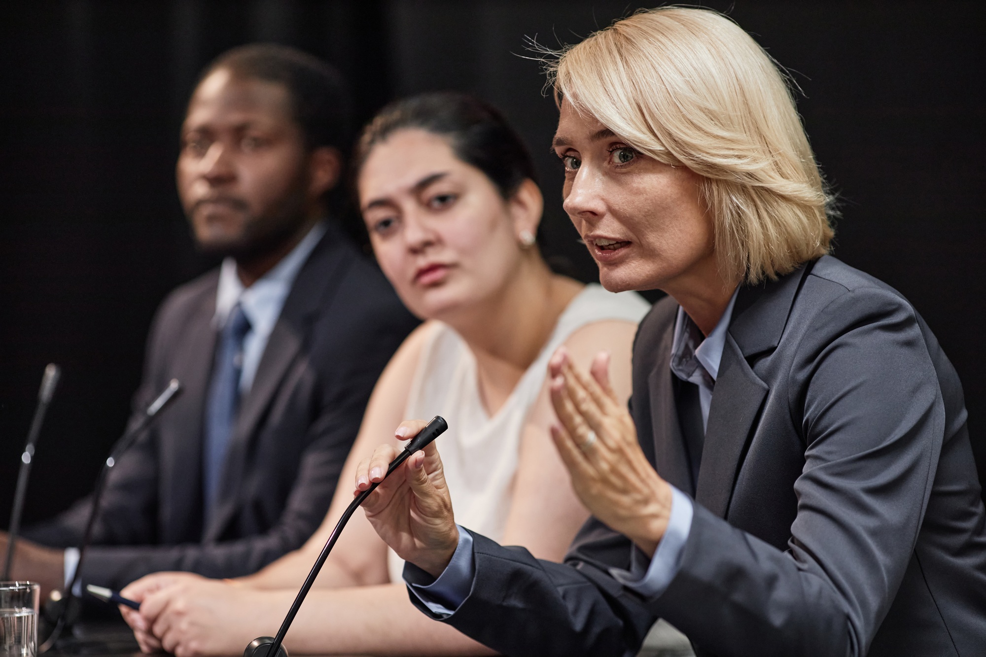 Female Politician Giving Speech on Draft Law Sitting in Line with Colleagues during Press Conference